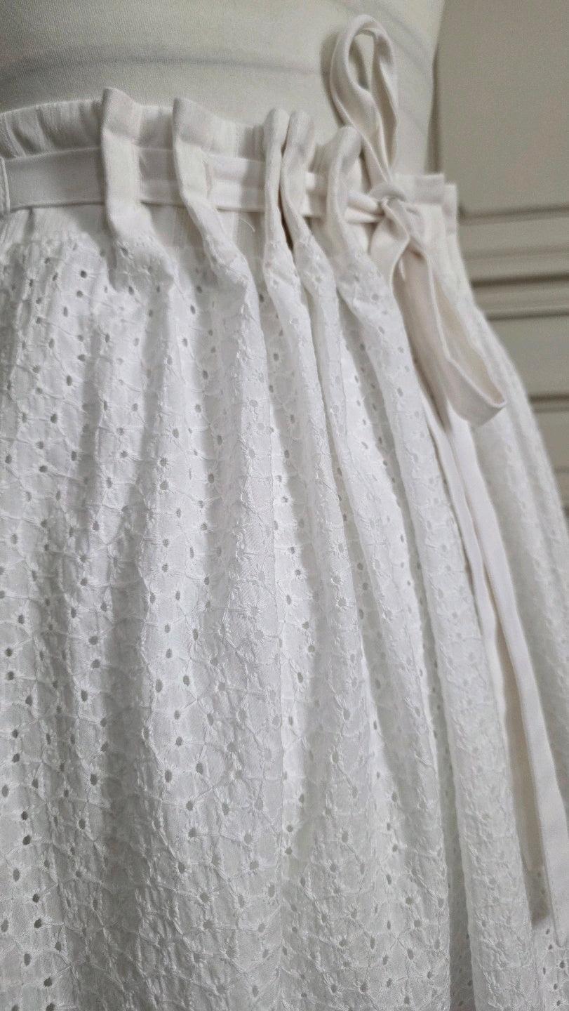 Jupe Alizé en broderie anglaise blanche, gros plan sur la taille ajustable par liens et les plis de la ceinture.
