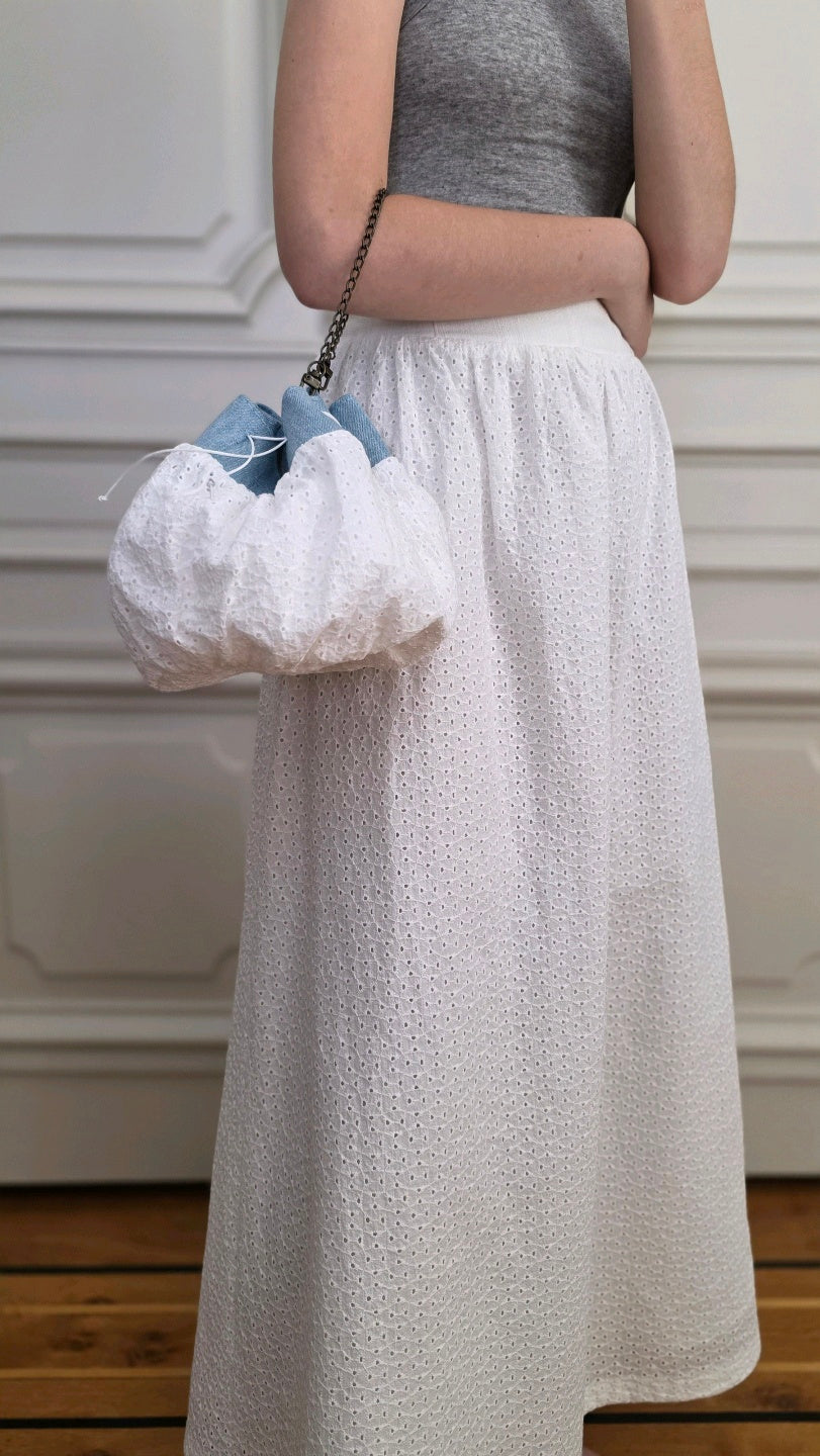 Jupe Alizé en broderie anglaise blanche portée avec un sac bourse assorti de la collection Corpus.