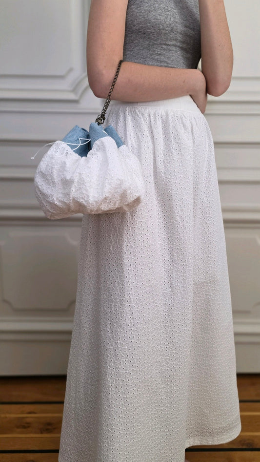 Jupe Alizé en broderie anglaise blanche portée avec un sac bourse assorti de la collection Corpus.