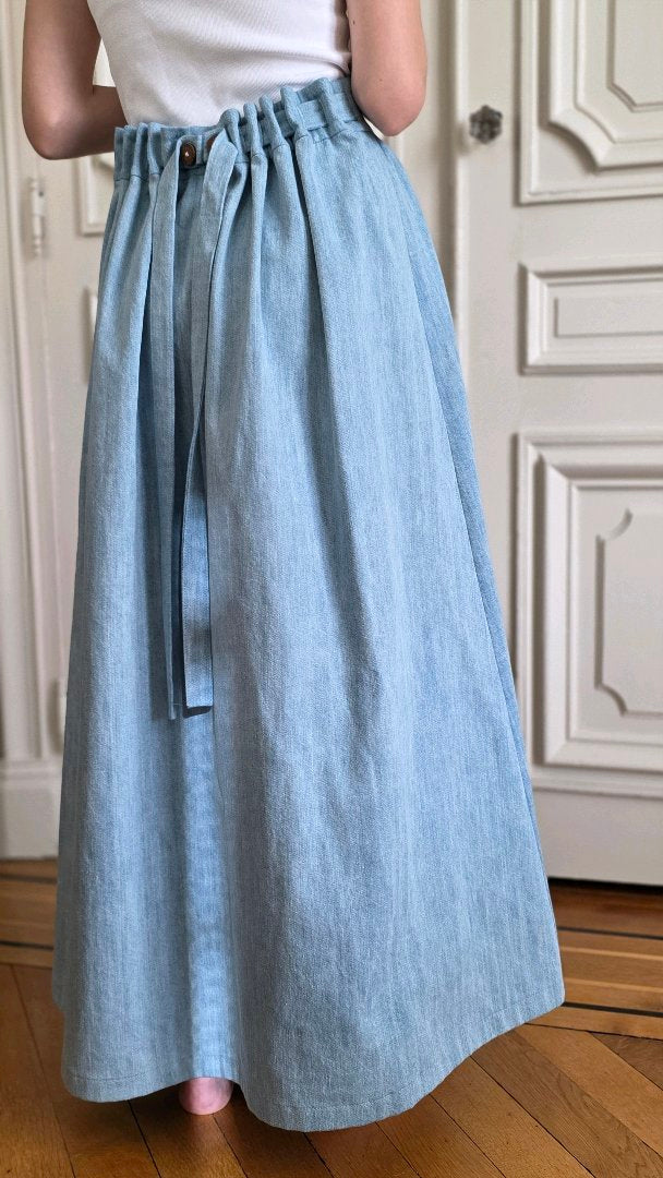 Dos d'une jupe longue en jean délavé avec taille réglable, liens à nouer et plis ajustables par boutons