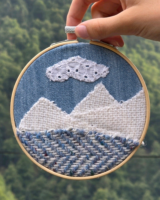 Échappée n°8, petit tableau textile en patchwork de denim et tweeds Mahlia Kent et Donegal, tenu devant un paysage