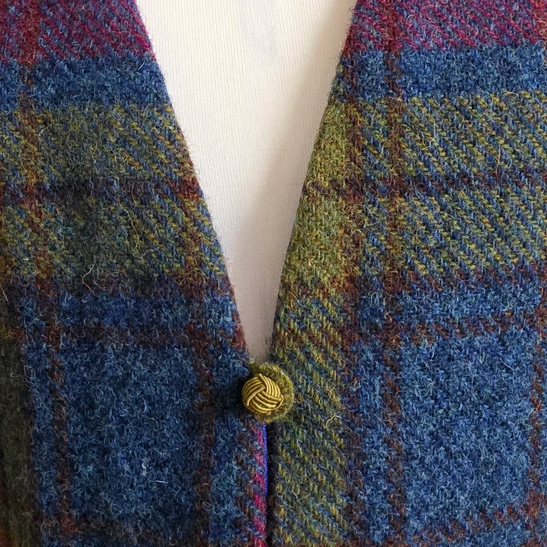 Détail de la bride brodée à la main et du petit bouton assorti du petit boléro sans manches en véritable Harris Tweed® et soie Odette.