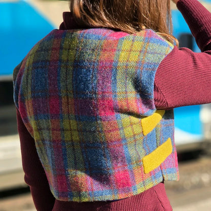 Photo extérieure du boléro sans manche Odette porté de dos par une femme sur le quai d'une gare