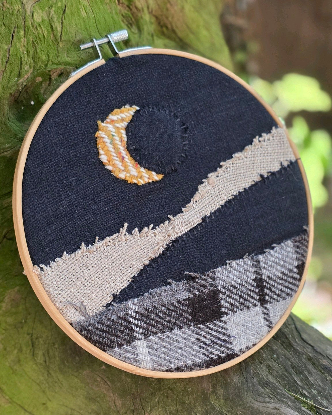 Échappée n°11, paysage textile en patchwork de lin, Harris Tweed® et Donegal présenté contre un arbre
