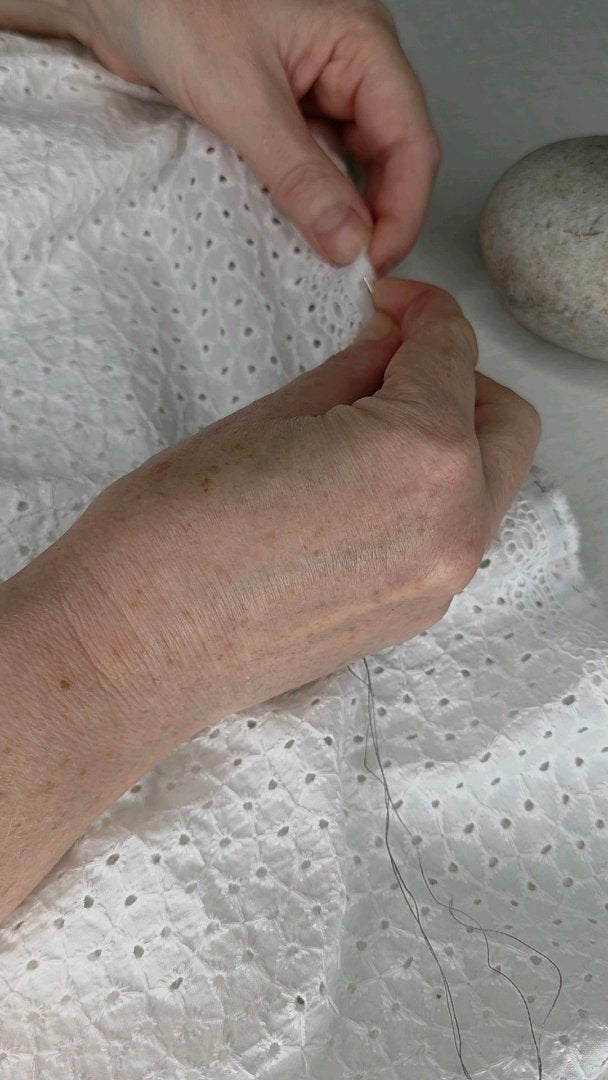 Finition artisanale à la main d'une jupe longue Alizé en broderie anglaise blanche.