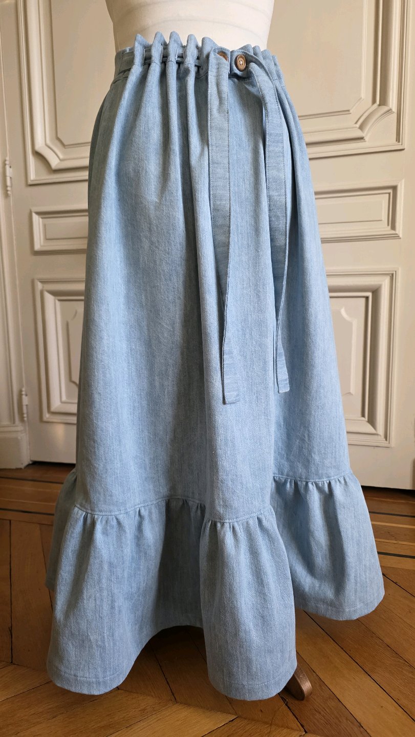 Version à volant de la jupe longue Bleu d'atelier en denim délavé avec taille ajustable, boutons en bois et liens à nouer