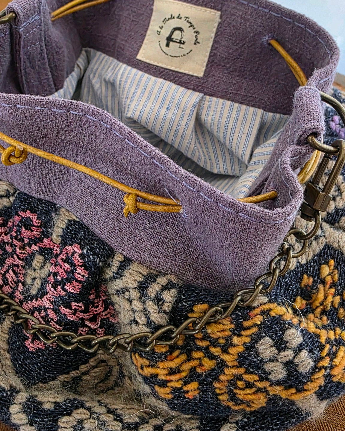 Détail du haut en lin mauve, des liens en cuir et de la doublure rayée du sac bourse en jacquard fantaisie Mahlia Kent.