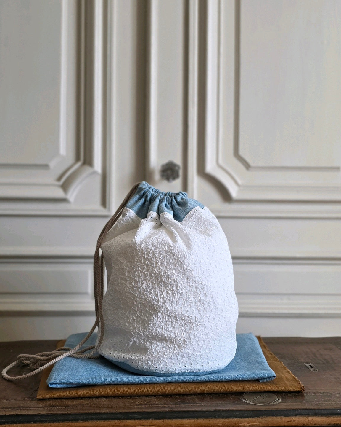 Grand sac baluchon en coton, broderie anglaise blanche associée à un denim bleu clair.