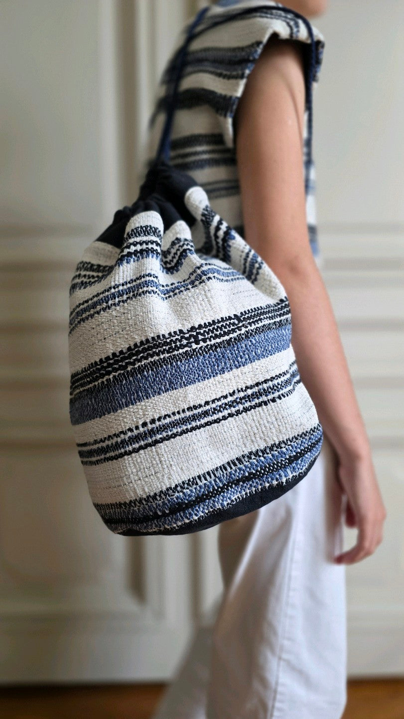 Sac baluchon artisanal en tweed marin bleu et écru Mahlia Kent porté à l'épaule.  Atelier A la Mode du Temps Perdu 