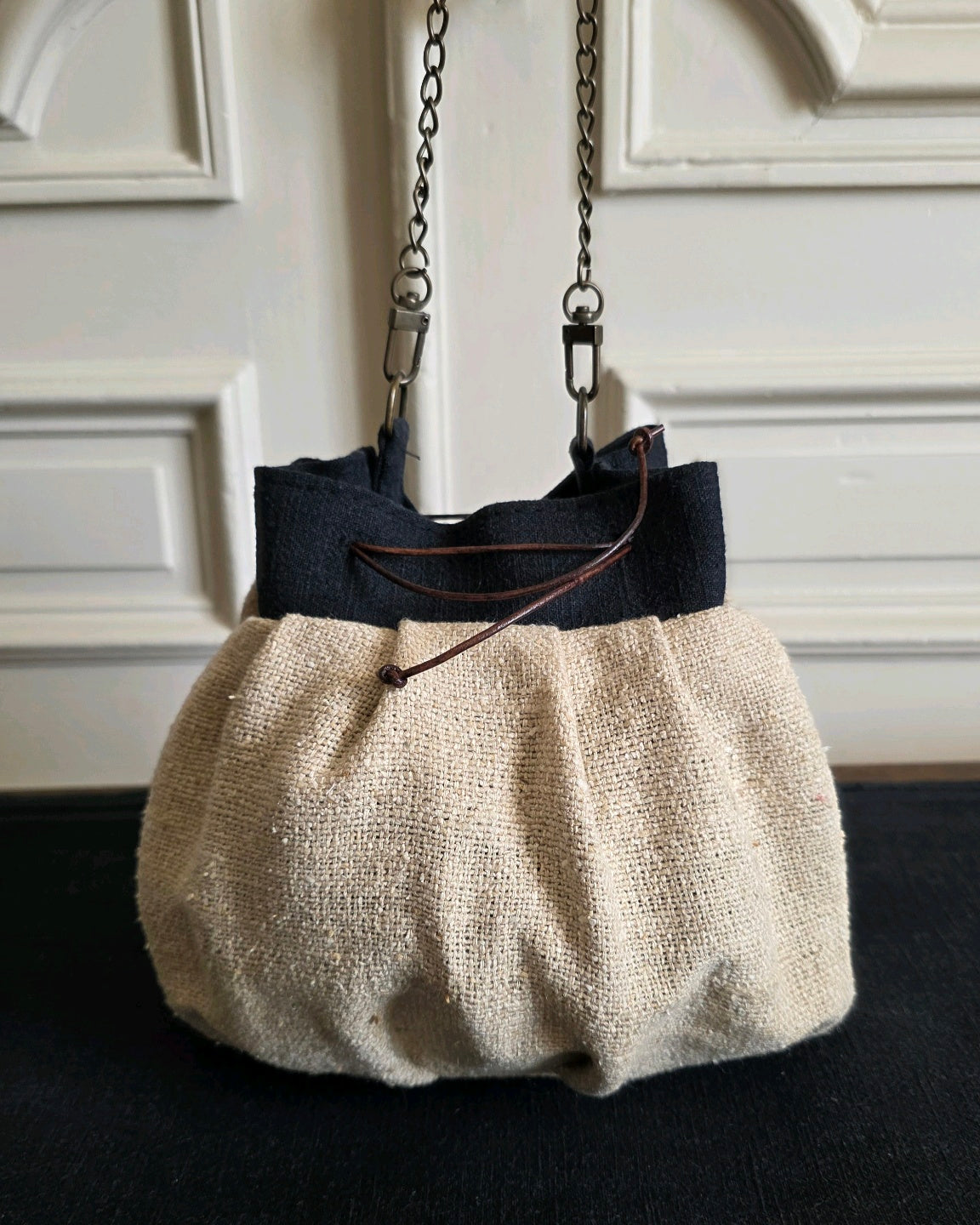Sac bourse en bourette de soie naturelle suspendu par sa chaînette en laiton vieilli, fermeture par liens en cuir.