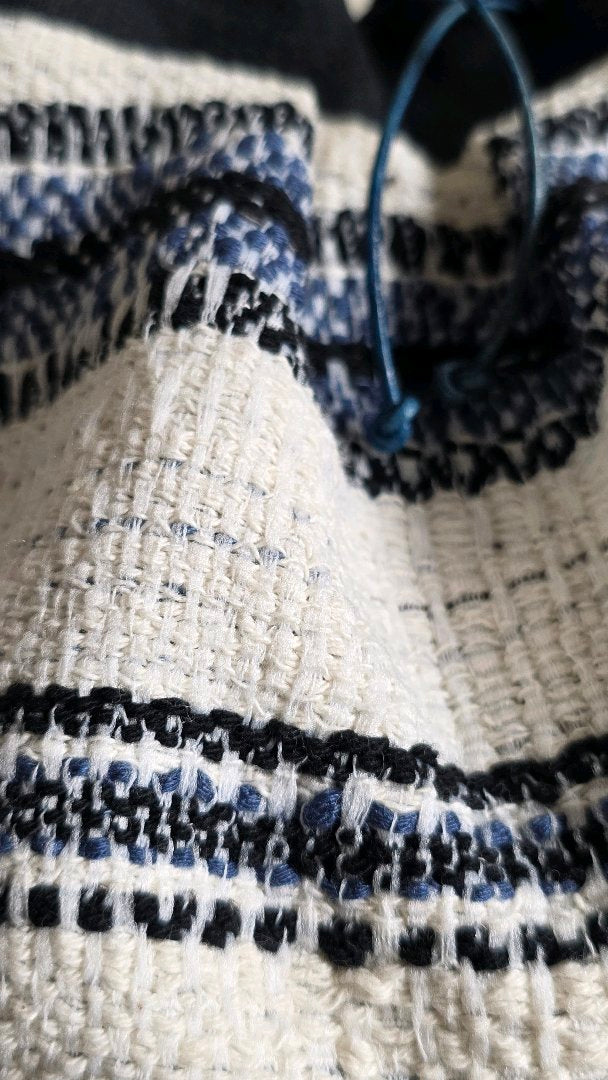 Gros plan sur le tweed bleu et écru du sac bourse artisanal en lin et coton