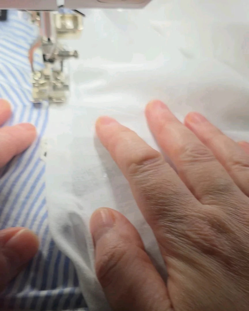 Couture en cours du top Alizé à la machine, geste d’atelier, mains au travail sur broderie anglaise, fabrication artisanale