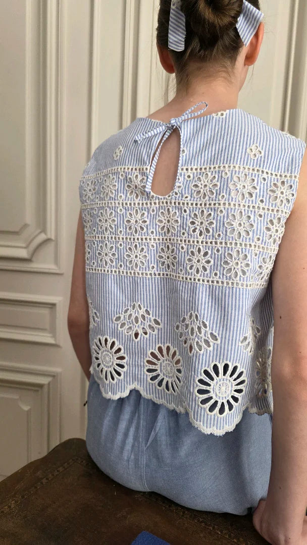 Top Alizé porté vue de dos en broderie anglaise bleu rayé, ouverture goutte et lien noué, détail dos été