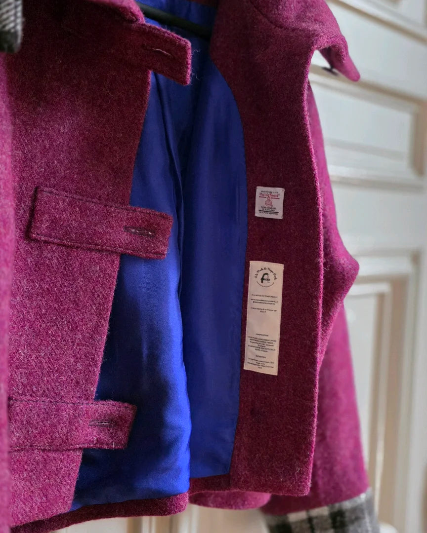 Profil veste Albertine Harris Tweed framboise.
Détail doublure soie et étiquette Harris Tweed Orb.
Photographiée devant portes blanches.