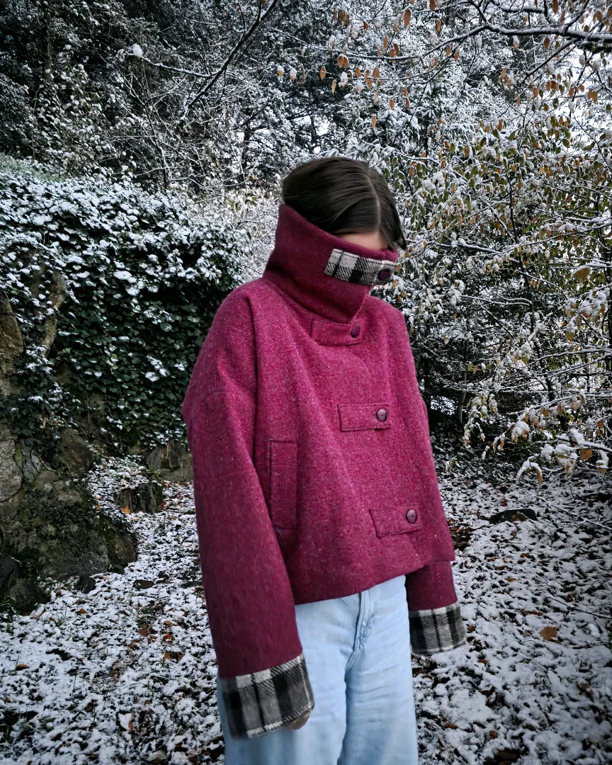 Veste Albertine Harris Tweed framboise vue 3/4 en extérieur neige.
Épaule tombante et volume oversize visibles.
Devant et côté bien détaillés.