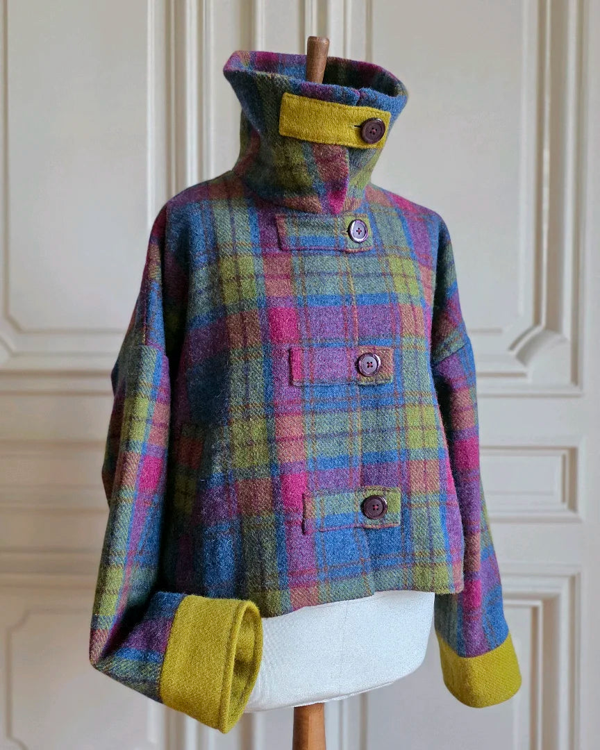 Veste artisanale Harris Tweed tartan vue de trois-quarts, col montant fermé par une bride en tweed uni contrastant, sur mannequin haussmannien.