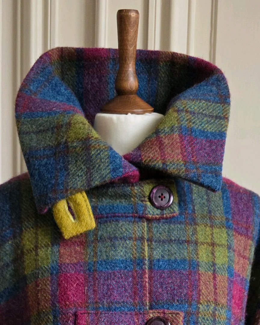  Détail du col montant ouvert de la veste Harris Tweed tartan et soie Gilberte, sur mannequin devant portes blanches haussmanniennes.

