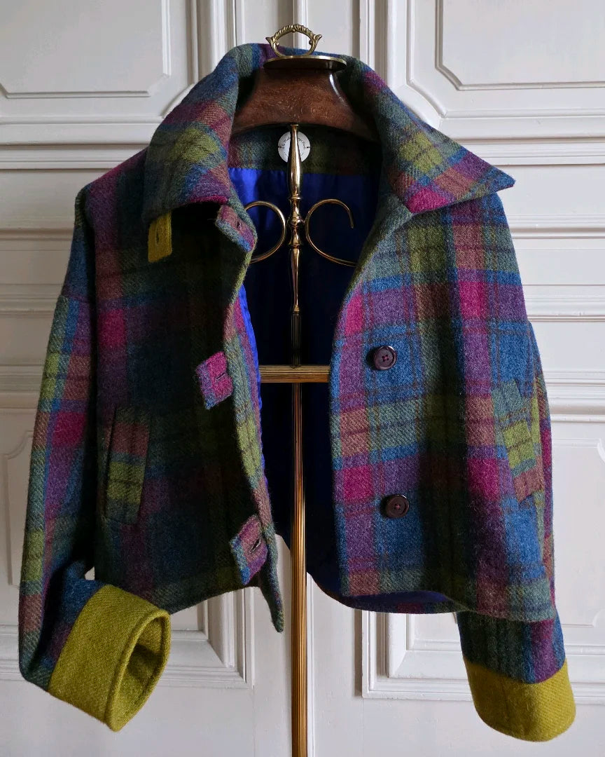 Veste femme Harris Tweed et soie Gilberte, présentée ouverte sur un valet doré devant des portes haussmanniennes blanches.