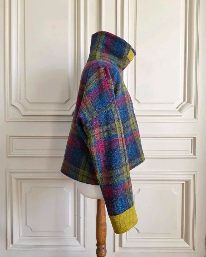 Veste femme Harris Tweed et soie vue de côté, col montant fermé, épaule tombante et bracelet de manche contrastant sur mannequin intérieur haussmannien.