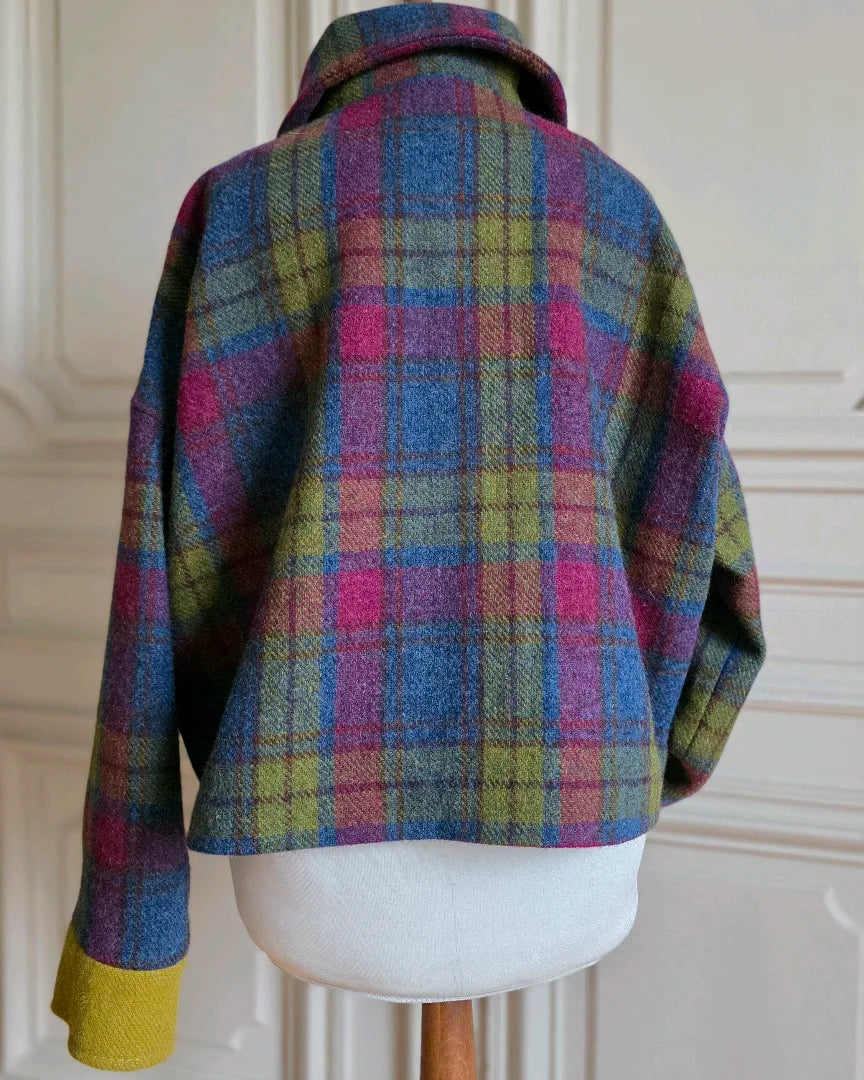 Veste Gilberte en Harris Tweed vue de dos, col replié, sur mannequin devant grandes portes blanches haussmanniennes.