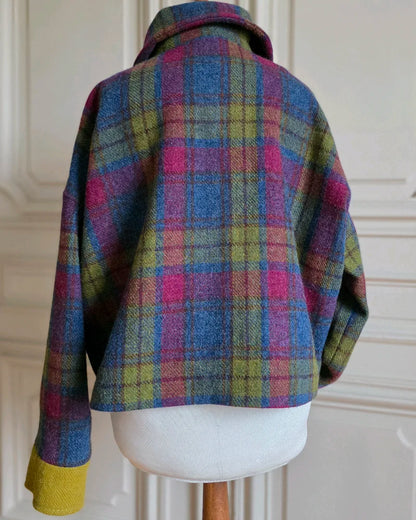 Veste Gilberte en Harris Tweed vue de dos, col replié, sur mannequin devant grandes portes blanches haussmanniennes.